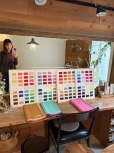 木の温もりある空間に、4シーズン（スプリング・サマー・オータム・ウィンター）のカラーチャートとドレープが並ぶパーソナルカラー診断の準備風景。鏡越しにサロンの落ち着いた雰囲気が映し出されている。