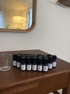 横浜市鶴見区のプライベートサロンiroka。コスモスコープで使用するさまざまな精油が、木製のテーブルにずらりと並んでいます。壁の鏡には温かな照明が映り、落ち着いたサロンの雰囲気が伝わる一枚です。